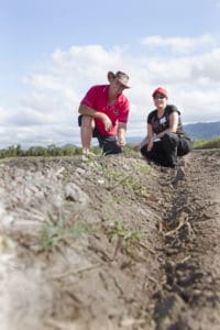 Man and woman squatting in field.